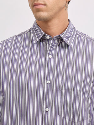 Man wearing an indigo color cotton oversized striped shirt with rolled sleeves, front pocket, and button-down collar
100% cotton
