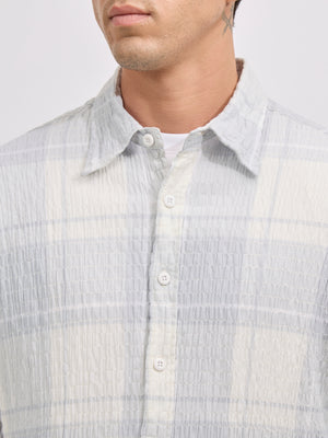 Men's oversized pale blue checkered cotton shirt with full sleeves, styled with grey trousers – casual fashion look