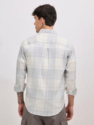 Men's oversized pale blue checkered cotton shirt with full sleeves, styled with beige trousers – casual fashion look