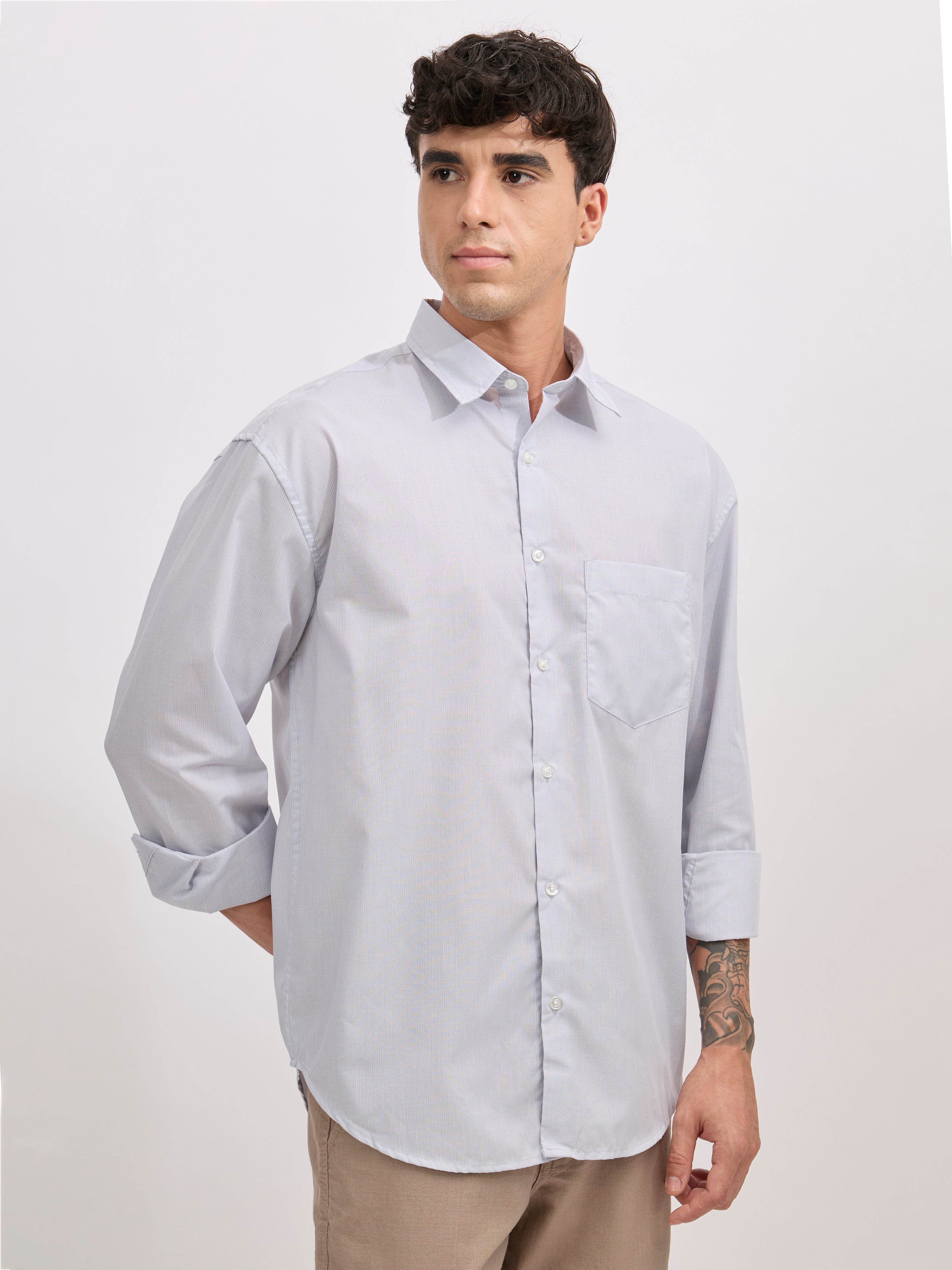 Man wearing grey cotton oversized striped shirt with rolled sleeves, front pocket, and button-down collar
100% cotton.