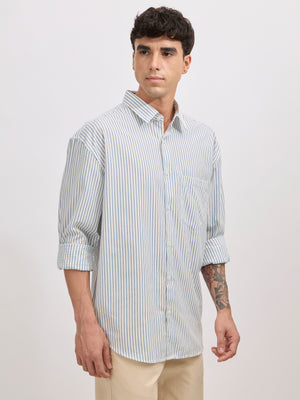 Man wearing a blue cotton oversized striped shirt with rolled sleeves, front pocket, and button-down collar
100% cotton