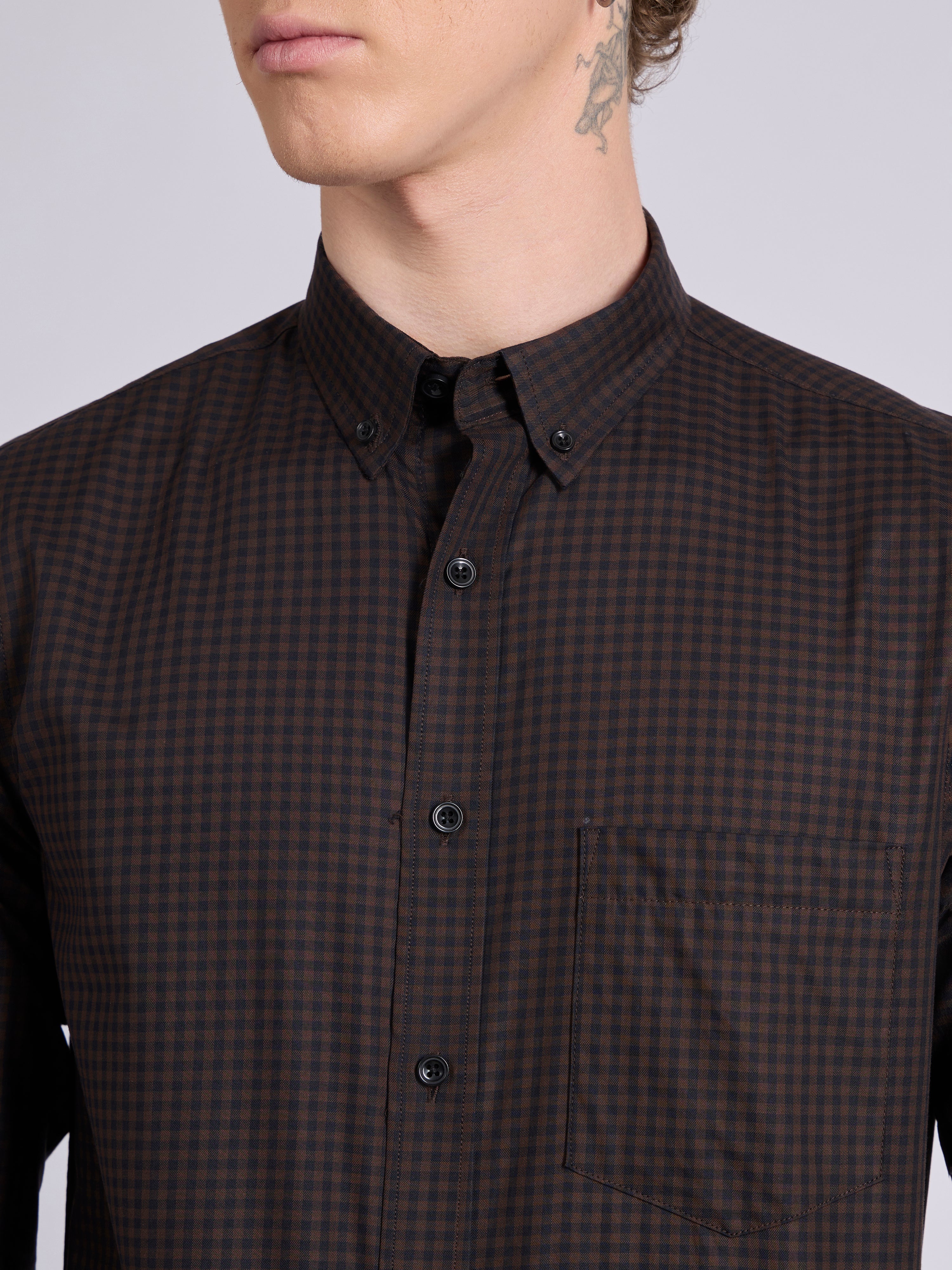 Man wearing a dark brown micro checkered shirt .