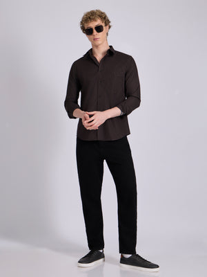 Man wearing a dark brown micro checkered shirt .