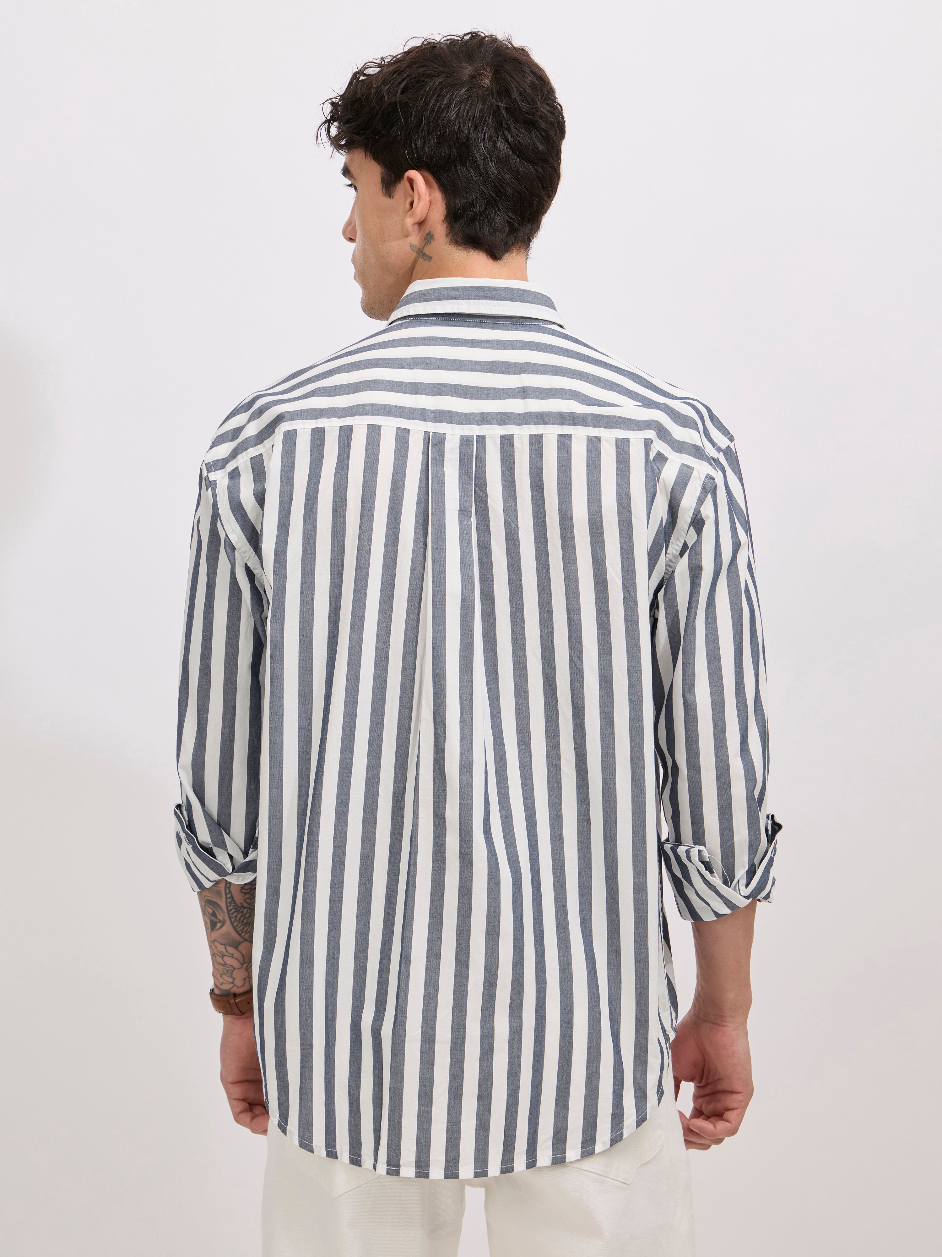 Man wearing a monochrome cotton oversized striped shirt with rolled sleeves, front pocket, and button-down collar
100% cotton
