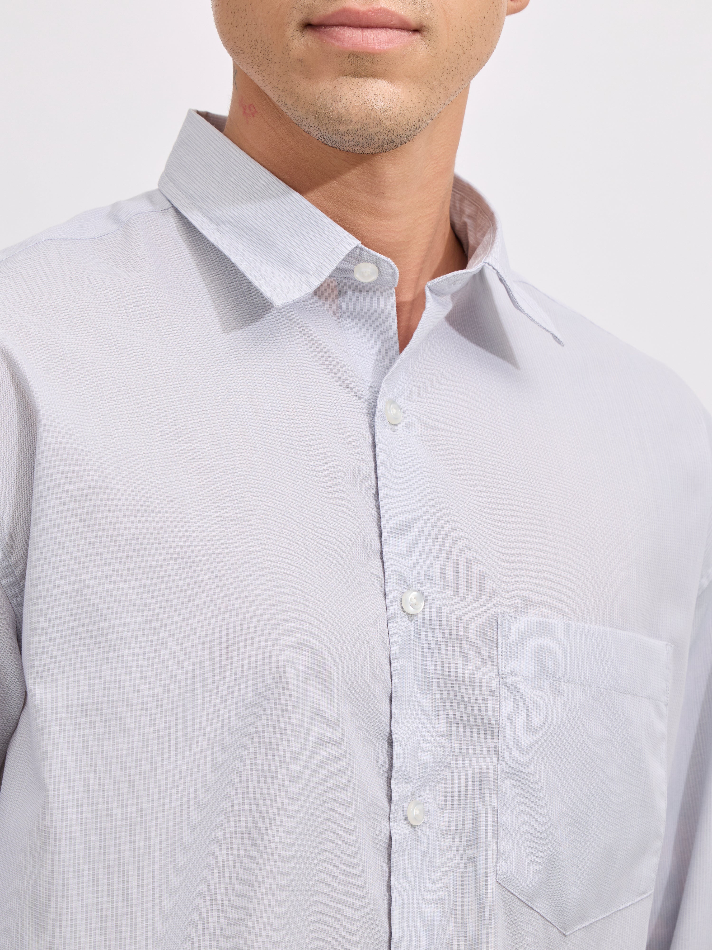 Man wearing grey cotton oversized striped shirt with rolled sleeves, front pocket, and button-down collar
100% cotton
