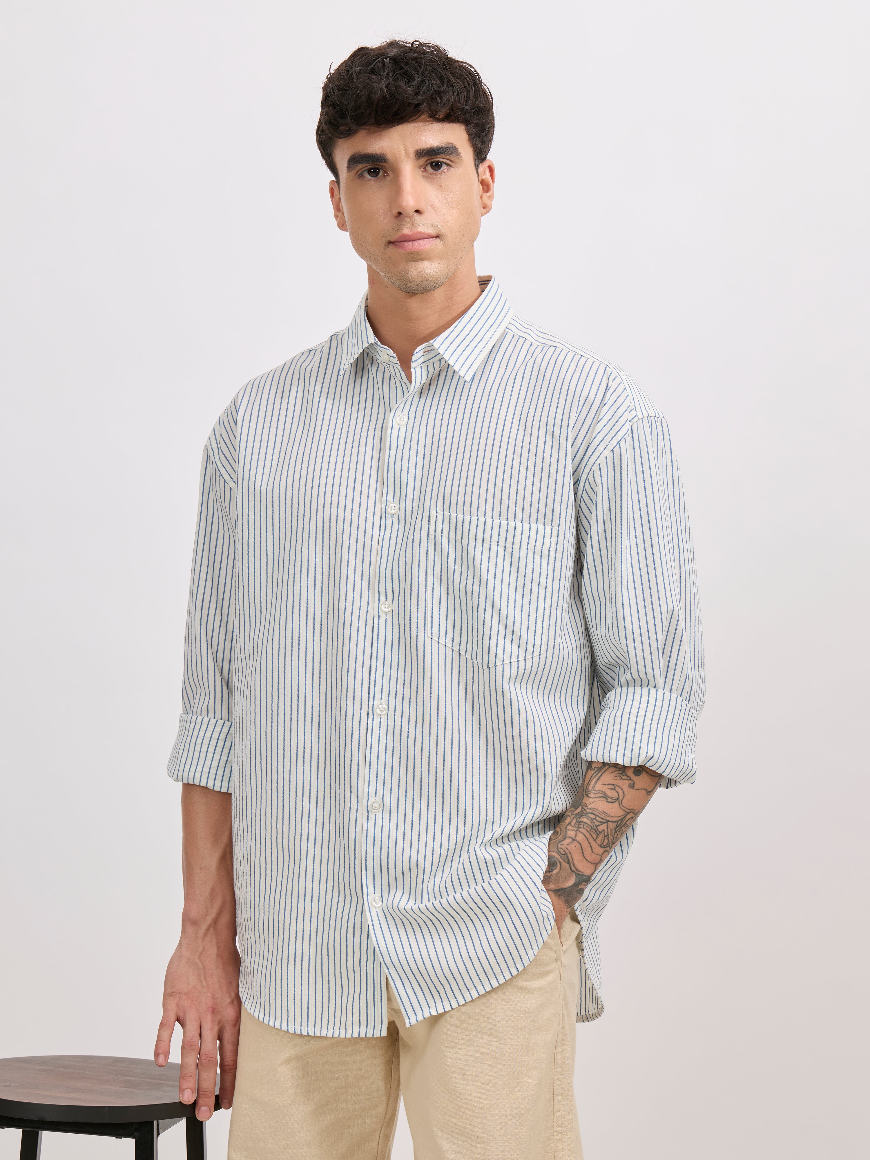 Man wearing a blue cotton oversized striped shirt with rolled sleeves, front pocket, and button-down collar
100% cotton
