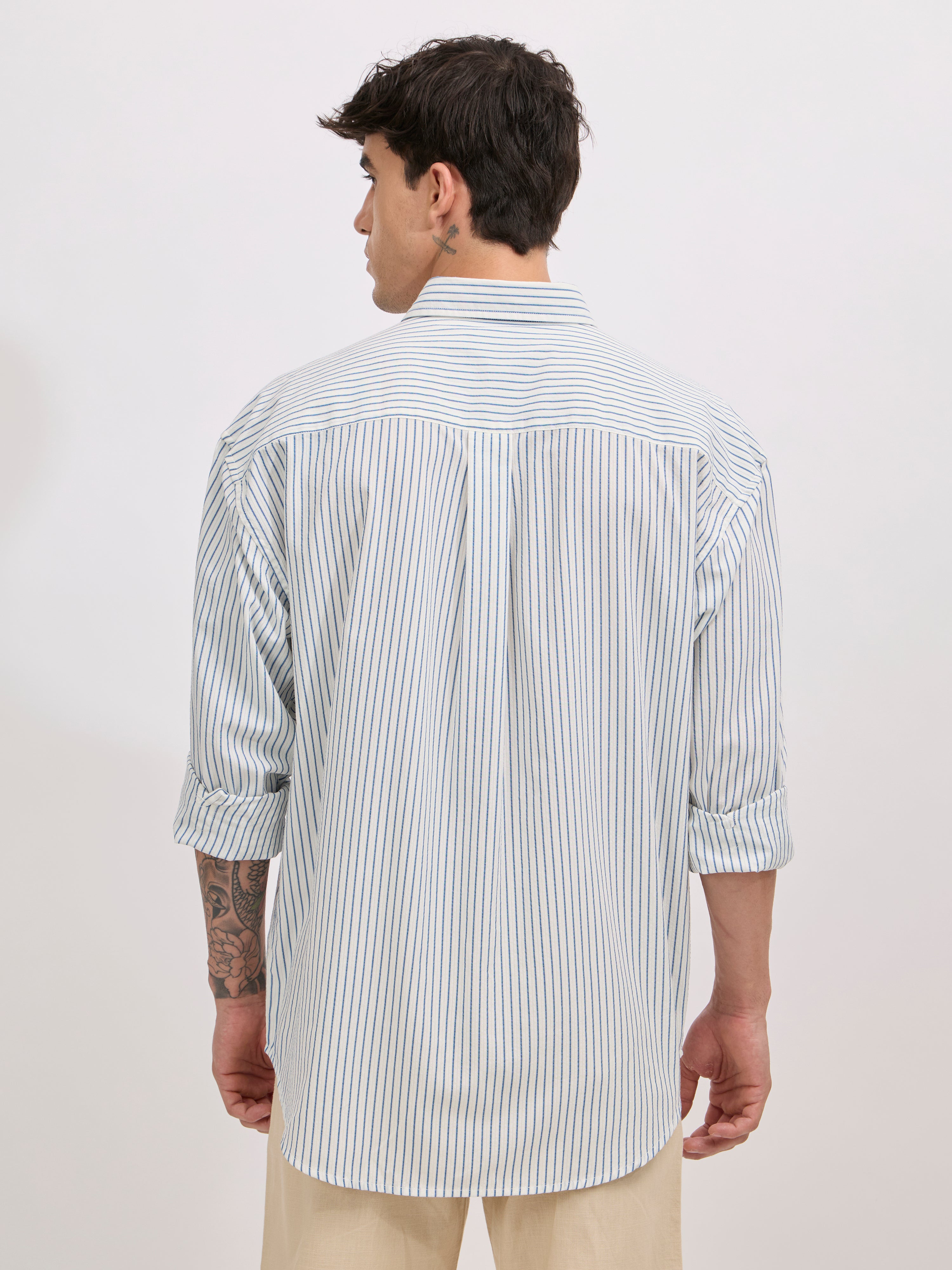 Man wearing a  blue cotton oversized striped shirt with rolled sleeves, front pocket, and button-down collar
100% cotton
